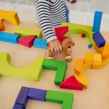 Dijete slaže šarene drvene kocke Grimm's na podu u kreativnoj igri